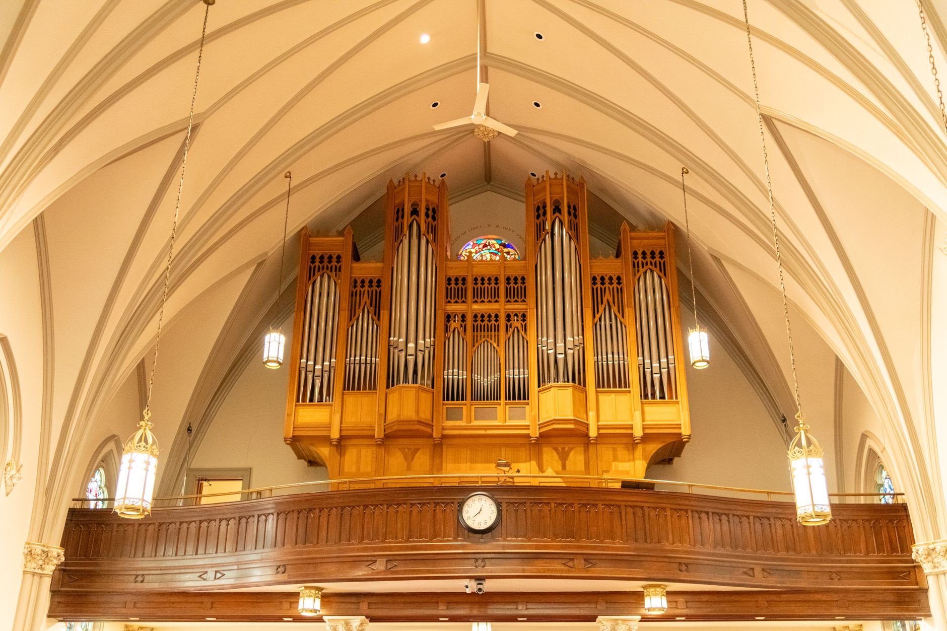 Ornate church interior featuring a large wooden pipe organ under vaulted ceilings.